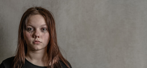 Naklejka premium Portrait of a sad teenager on gray background. Empty space for text