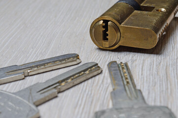 the disassembled door lock and the keys to it lie on a light surface. close-up.