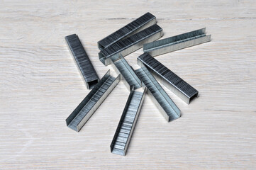 a bunch of staples for an industrial stapler lie on the tabletop.
