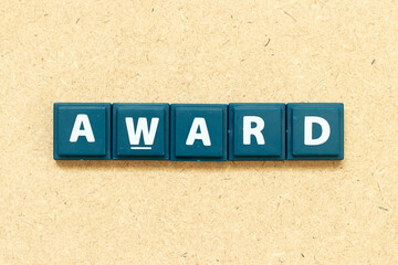 Tile alphabet letter in word award on wood background