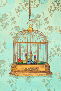 Vintage birdcage with old figurine birds in front of wallpaper with flower pattern