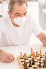 Senior man wearing protective face mask plays chess with his friends during quarantine Coronavirus (Covid-19) epidemic