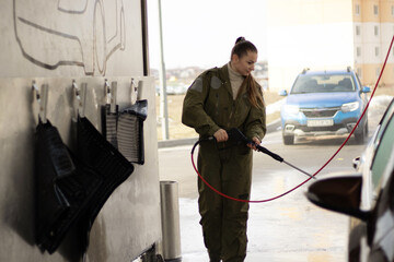 A woman washing a car using a high-pressure water system. 