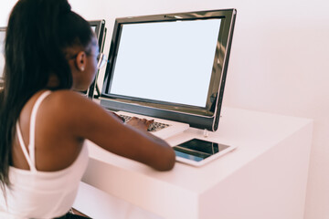 Skilled female student using blank PC technology for informative research in computer class of university connecting to public internet for browsing, woman reading web publication on mockup device