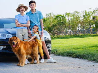 Happy family of three and pet dog in front of car