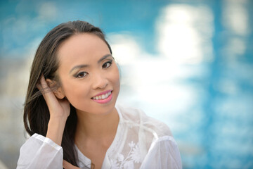 Ritratto di una ragazza vietnamita sorridente vestita di bianco vicino alla piscina
