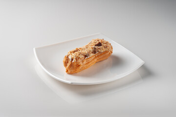 Eclair with buttercream on a white square plate