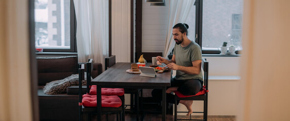 A man is having breakfast at home with a tablet.