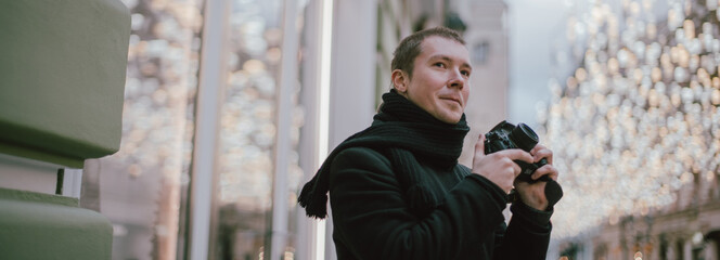 A man with a camera photographs the street of the old city in winter