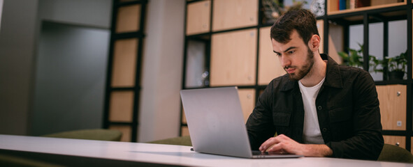 A man works on a laptop in an office or coworking