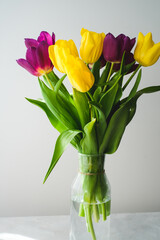 Lilac purple tulip flowers on table. Spring bouquet flowers in vintage vase. Floral concept. Floral background.  White decoration and light background