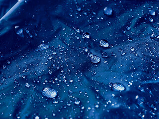 Water drops on waterproof membrane fabric. Detail view of texture of blue waterproof cloth.