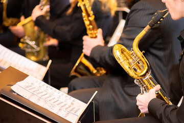 The orchestra plays saxophones. Musician blowing the saxophone