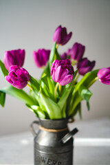 Lilac purple tulip flowers on table. Spring bouquet flowers in vintage vase. Floral concept. Floral background.  White decoration and light background