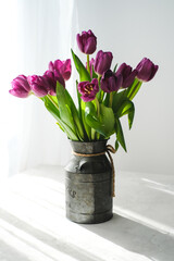 Lilac purple tulip flowers on table. Spring bouquet flowers in vintage vase. Floral concept. Floral background.  White decoration and light background