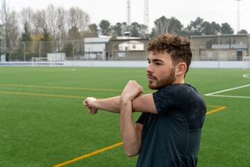 Young athlete wearing sports clothes stretching in stadium after work out.