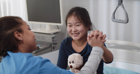 African nurse playing with sick asian girl in hospital ward