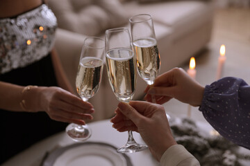 People clinking glasses with champagne at home, closeup