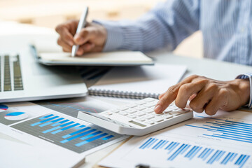 close-up of a male accountant or banker who notes and checks investment results, calculates financial savings, calculates annual taxes and economic concepts. Financial calculation concept