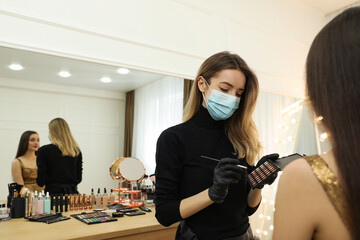 Professional makeup artist working with client in salon. Beauty services during Coronavirus...