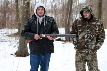Twin brothers with a shotgun in the winter forest