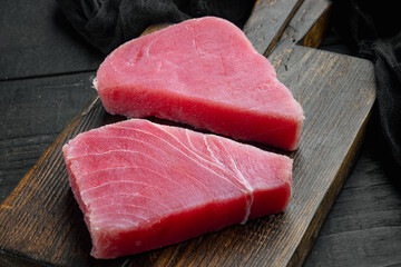 Obraz na płótnie Canvas Raw tuna steak, on wooden cutting board, on black wooden background