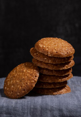 A stack of sesame cookies on a dark background, in detail
