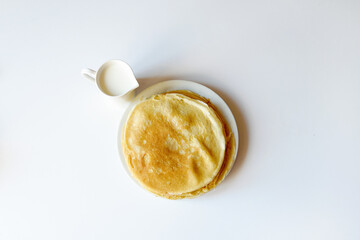 A lot of pancakes are stacked on a white plate. Thin pancakes with a crispy crust. Pancake day.