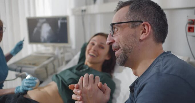 Gynecologist performing ultrasound scanning for pregnant couple