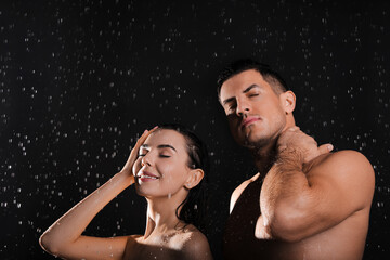 Couple taking shower against black background. Woman washing hair