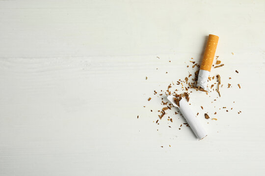 Broken cigarette on white table, flat lay with space for text. Quitting smoking concept