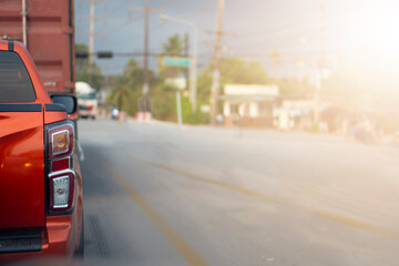 Transportation concept. Rear side of orange car stop on the asphalt road.  Waiting quary from traffic light control at junction in day time.
