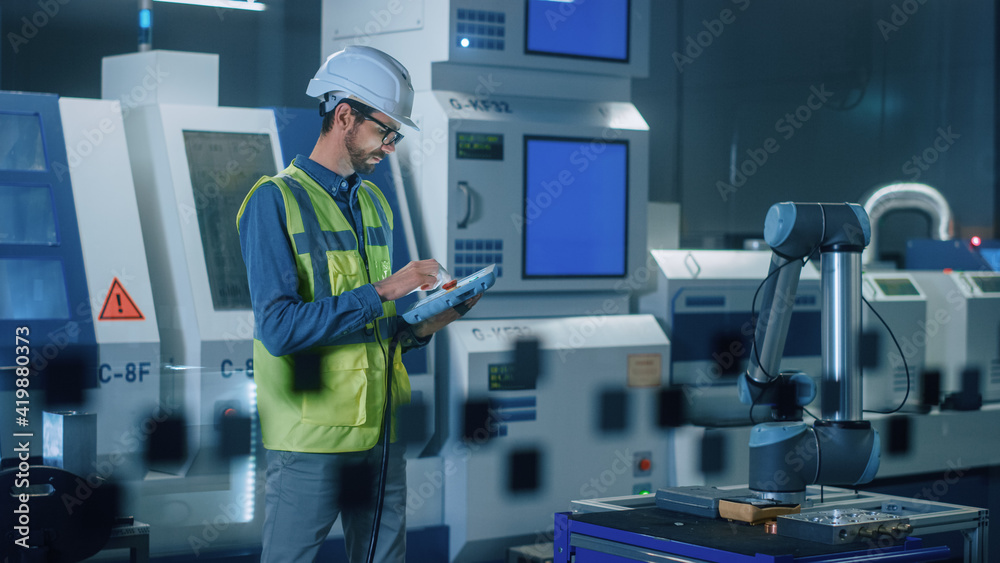 Poster portrait of professional engineer wearing safety vest and hardhat, uses industrial digital tablet to