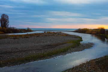 The river flows into the sea. View of the riverbed of the Mzymta River, which flows into the Black Sea, Adler district of Sochi, Russia. mountain river flowing to the sea