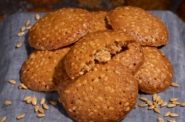 A pile of sesame cookies on a gray canvas napkin