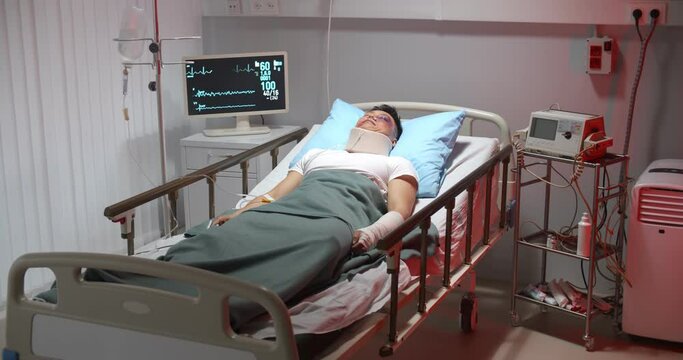 Young male patient with neck collar and bruised face lying unconscious in intensive care unit