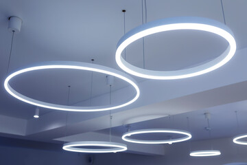 Ceiling with round modern LED lamps. Suspended fluorescent lights under the ceiling. Careful energy consumption, energy saving concept - obrazy, fototapety, plakaty