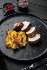 Grilled pork fillet and mash potatoe gratin with sage and prosciutto , on plate dish, on black wooden table background