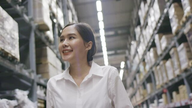 Smiling Asian woman happy walking shopping in mall or warehouse. Female staff member checking stock in the factory. Concept Shopping business 