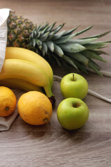 Linen tote bag with pineapple, bananas, lemons and apples. Selective focus.