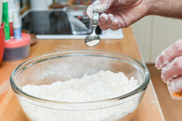 Person making bread in home kitchen adding ingredients to make the dough