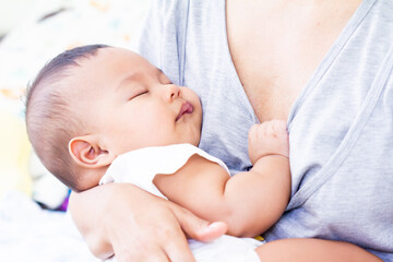 mother carried baby after the feeding.mother carried baby after the feeding.