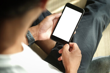 Close up view of male hands using smart phone with modern office blurred background. Blank screen monitor for graphic display montage.