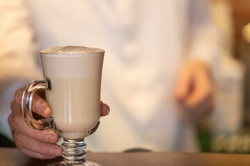 Coffee with milk latte, cocoa in a glass wine in a coffee shop in the hands of a barista. The drink is on the bar