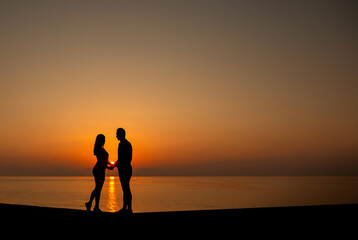 Silhouette of two young people on the beach in sunset