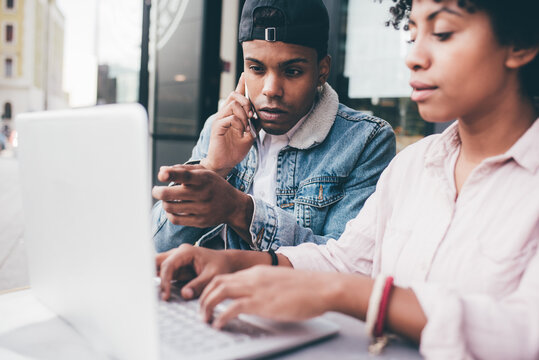 Young man and woman sitting outdoor using computer