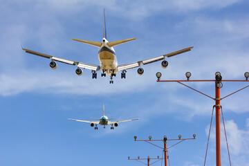 rear view of two airplanes for commercial passenger or cargo transportation aircraft flying in sequence and spread the wheel for landings to airport on blue sky