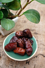 Dates fruit in a wooden bowl closeup on wooden background