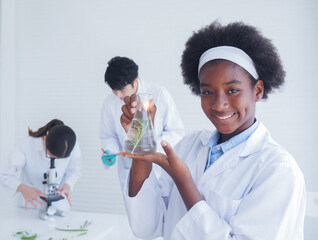 A dark-skinned student smiled happily as she shows the results of the experiments on plants in the...