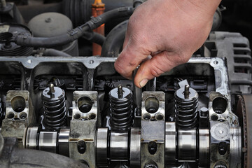 Car mechanic fixing modern diesel engine, closeup of hand with socket bit removing injectors from...